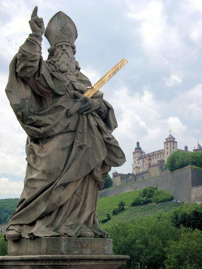 Statue: Kilian mit dem Goldenen Schwert, auf der Alten Brücke in Würzburg, im Hintergrund die Festung Marienburg