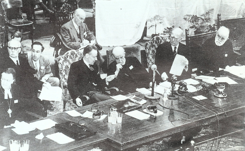 Gründungsversammlung des Ökumenischen Rates der Kirchen 1948 mit Geoffrey Fisher, dem Erzbischof von Canterbury (Mitte), Willem Visser 't Hooft (links daneben) und John Mott, dem Sekretär des Christlichen Vereins Junger Menschen, der zum Ehrenpräsidenten ernannt wurde (rechts daneben)