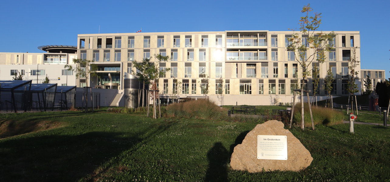 Heutiges Krankenhaus in Neunkirchen, davor der Gedenkstein für das im Krieg zerstörte frühere Gebäude