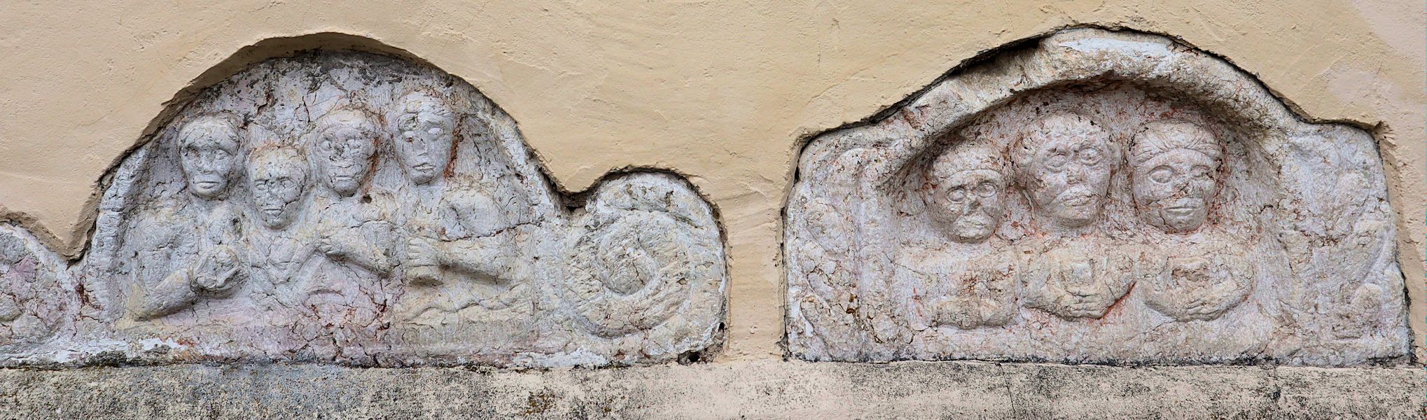 Sieben Köpfe auf römischen Grabsteinen, an der Kirche Rotthof