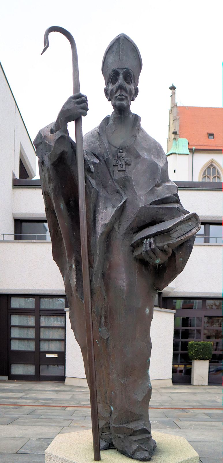 Klaus Backmund: Statue, 1993, vor dem Tagungshotel Haus Sankt Ulrich, erbaut an der Stelle des früheren Benediktinerklosters an St. Ulrich und Afra in Augsburg