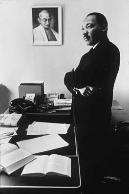 Martin Luther King in seinem Arbeitszimmer vor einem Bild von Gandhi