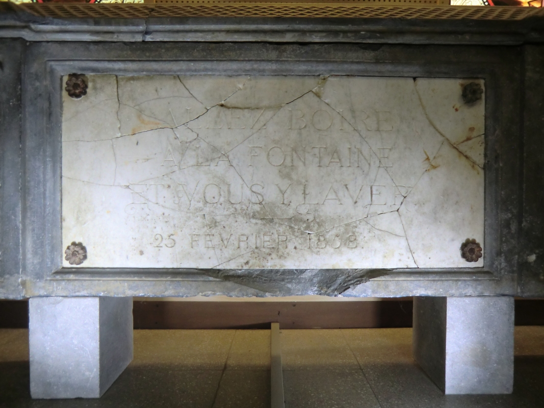 Der erste an der Quelle der Grotte errichtete Brunnen mit der Inschrift „Komm, trink an der Quelle und du wirst gereinigt” und dem Datum 25. Februar 1858, heute im Museum