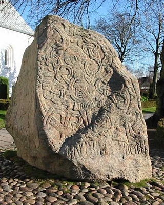Runenstein in Jelling, aufgestellt von Harald I., mit einem Bild von Jesus Christus. Inschrift: „König Harald gebot, dass dieses Denkmal seinem Vater Gorm und seiner Mutter Tyra gemacht wurde; der Harald, der sich ganz Dänemark und Norwegen unterwarf und die Dänen zu Christen machte.”