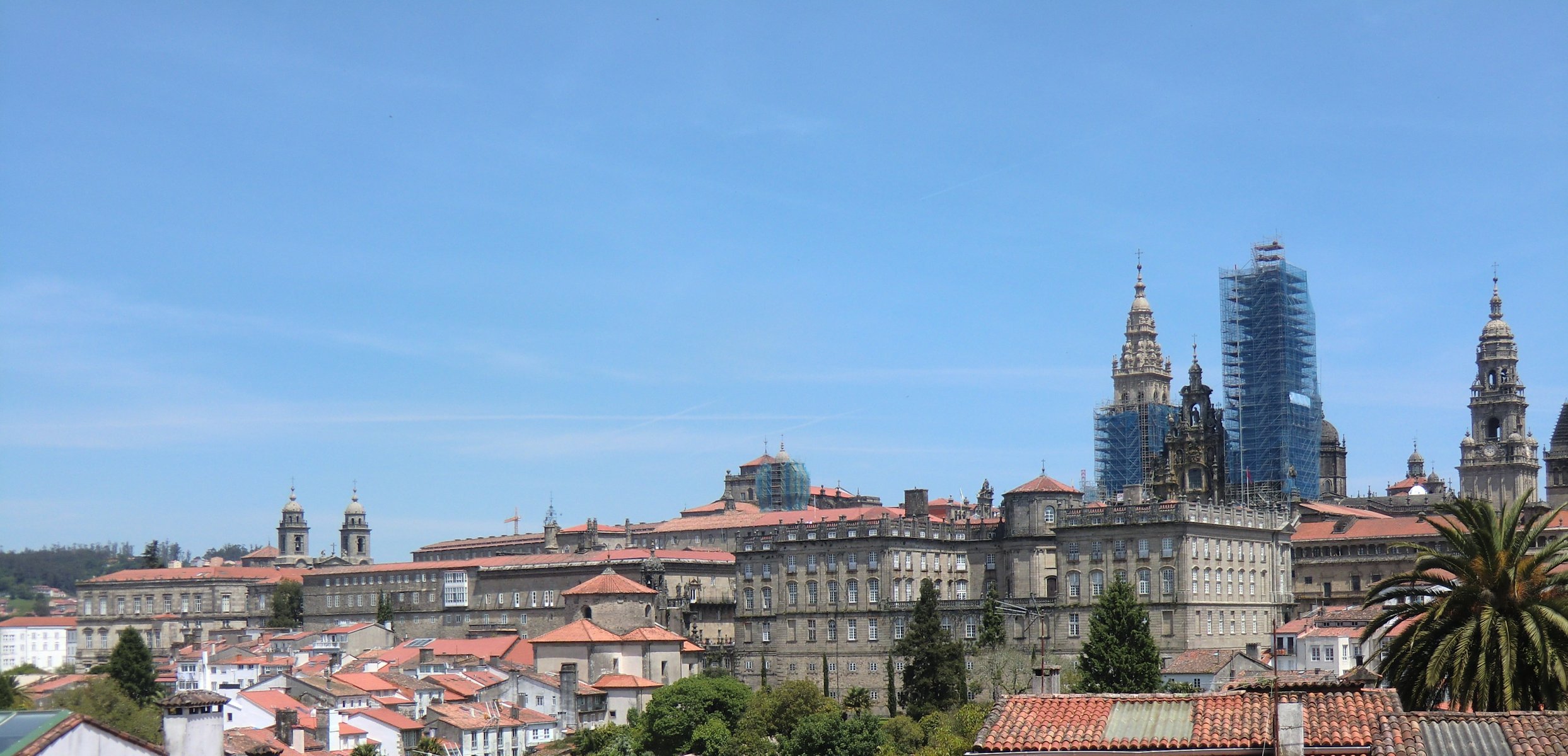 Blick auf die Kathedrale in Santiago de Compostela von Westen mit den Türmen der Franziskanerkirche (links), dem Palast „de Raxoi” für den Klerus aus dem 18. Jahrhundert, heute Rathaus der Stadt, links und dem Hieronymuskolleg aus dem 17. Jahrhundert, heute Universität (rechts)