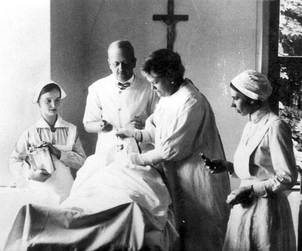 Dr. Batthyány bei einer Operation mit seiner Frau (halbrechts), die ihm assistiert