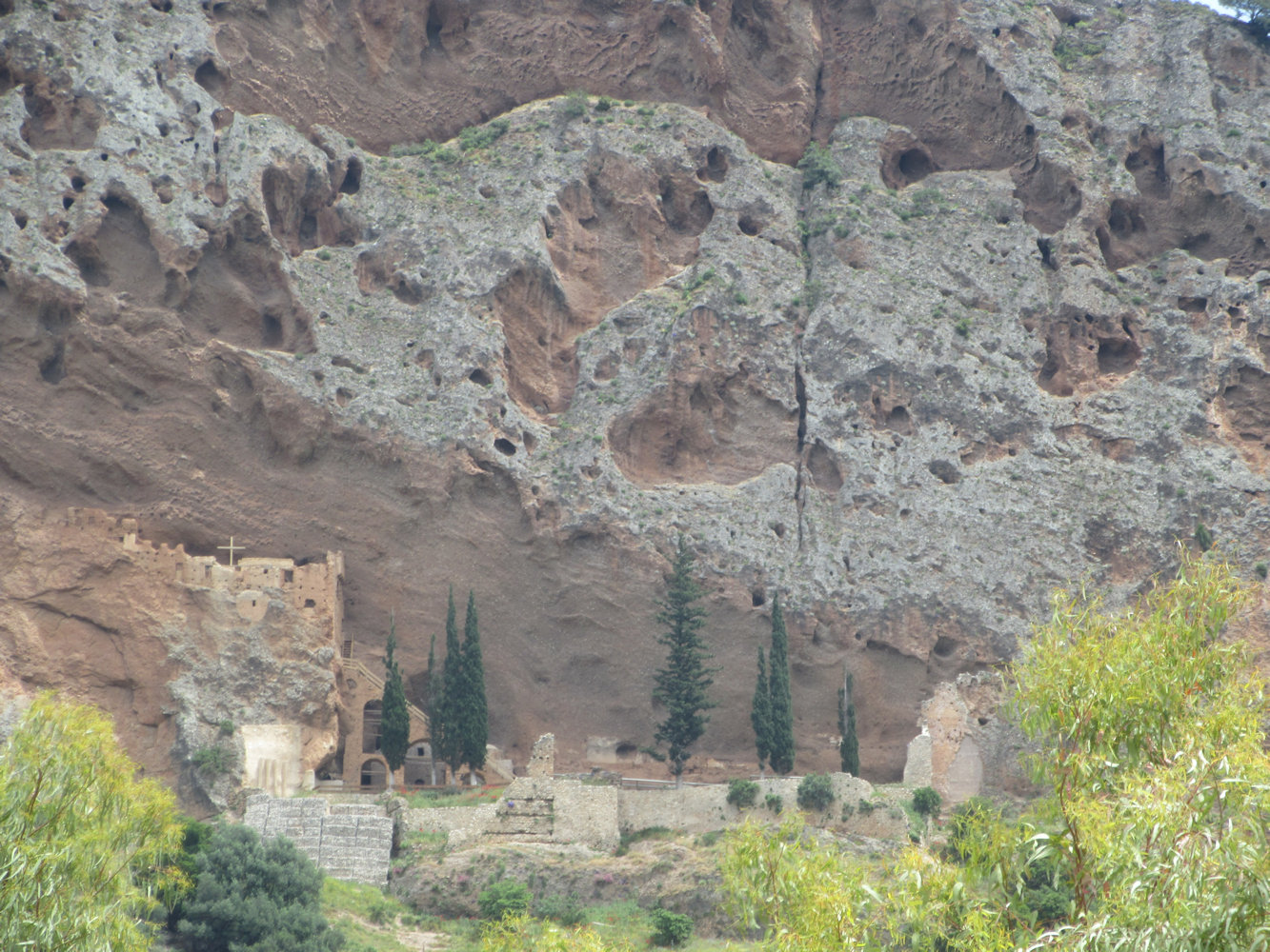 Leontios' in Ruinen liegendes Kloster am mit Höhlen übersäten Fels mit der intakten Kapelle (links)