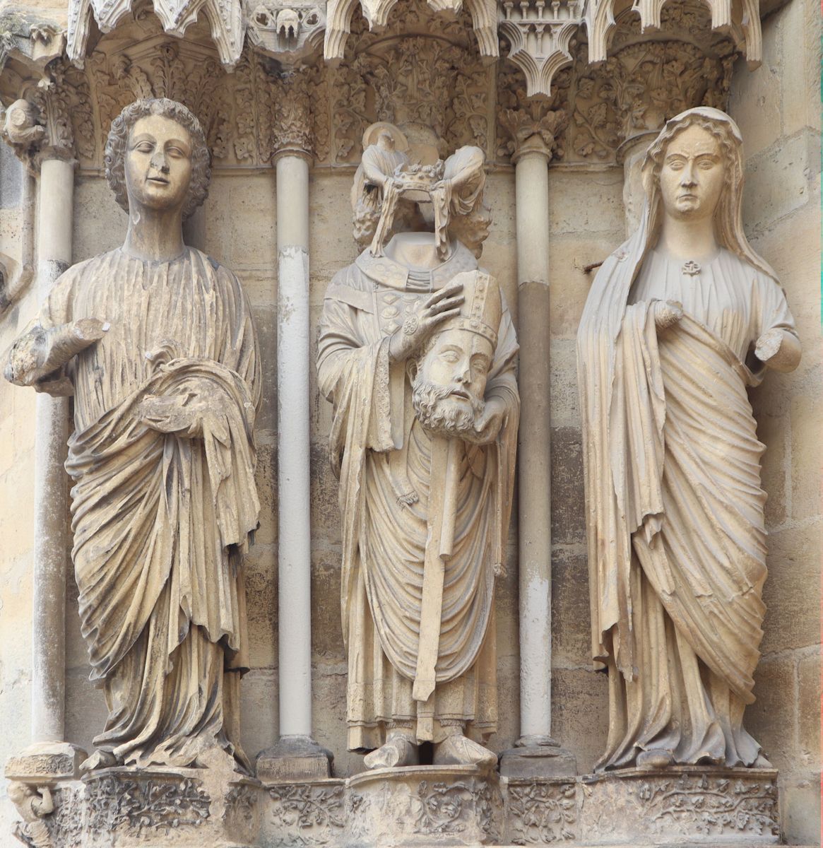 Statuen: Nikasius (Mitte) mit einem Engel und seiner Schwester Eutropia (rechts), um 1228, am rechten Nordportal der Kathedrale in Reims