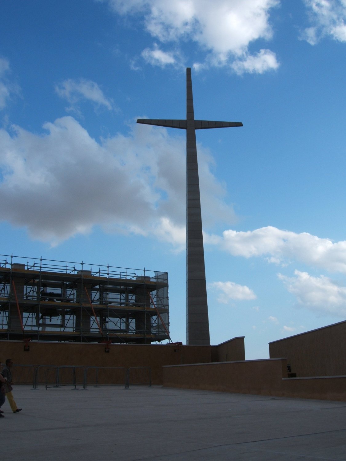 Das riesige Kreuz vor der neuen Kirche, weit in die Stadt und das Tal hinaus sichtbar, daneben die (eingerüsteten) Glocken