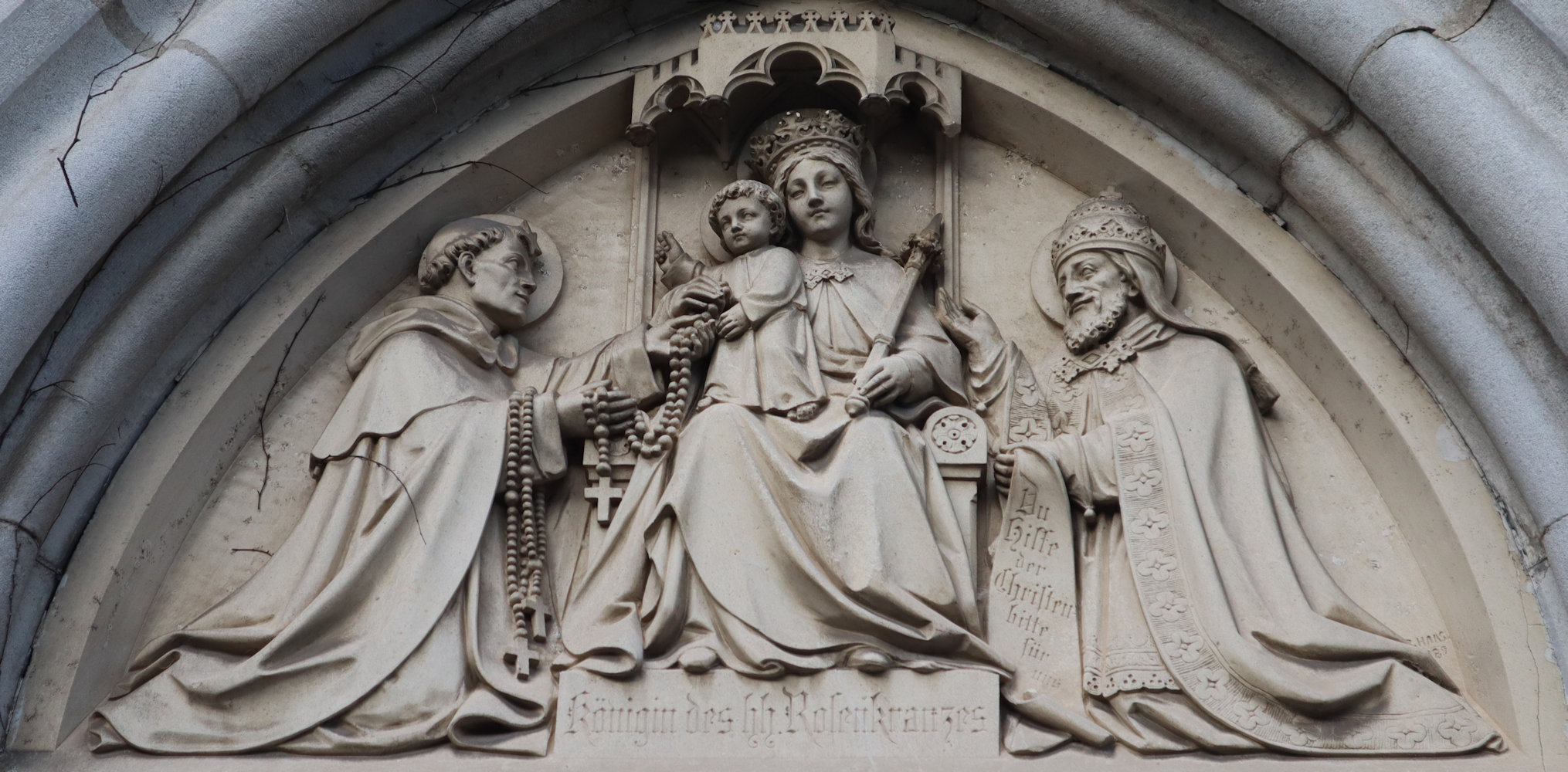 Tympanon: Dominikus (links), Maria als „Rosenkranzkönigin” und Pius, um 1890, an der Dominikanerkirche in Friesach in Kärnten