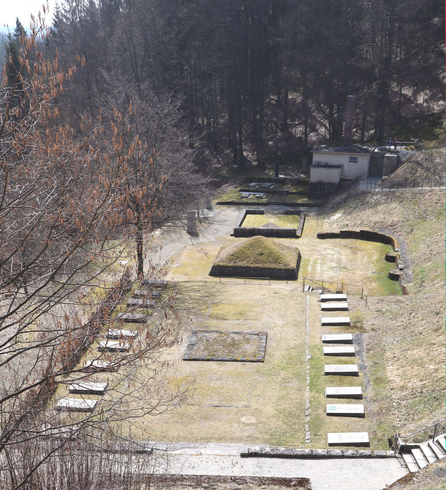 „Platz der Nationen” mit Gedenksteinen für die Ermodeten aus 35 Ländern und Aschehügel als Mahnmal, im Hintergrund das Krematorium im ehemaligen Konzentrationslager in Flossenbürg