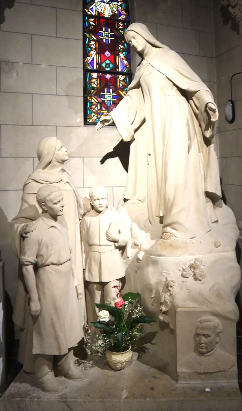 Statue: Eine Unbeschuhte Karmelitin bringt einen Erstkommunikanten und ein Waisenmädchen aus der &bdquo;Stiftung für verwaiste Lehrlinge von Auteil&brdquo; zu Theresia, in der Kapelle der &bdquo;Fondation des apprentis d'Auteuil&rdquo; im Pariser Stadtteil Auteuil